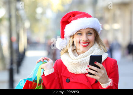 Vorderansicht Portrait Of Happy Shopper Shopping online an der Kamera auf der Suche nach Weihnachten auf der Straße Stockfoto