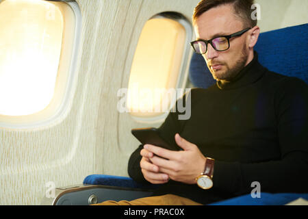 Mann mit Smartphone im Flug Stockfoto