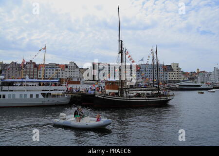 Boote und Yachten füllen den Hafen von Bergen in Norwegen während der Markt Tag (Torgdagen) Festival, während eine junge Familie mit einem Schlauchboot. Stockfoto