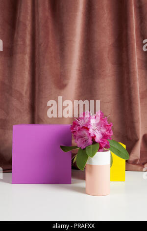 Bicolor Vase mit Blumen rosa Rhododendron innen und Würfel gefärbt. Minimale noch leben Farbe Fotografie Stockfoto