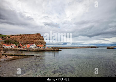 Staithes, North Yorkshire, England, 22. August 2018: Moody Himmel bei Sonnenuntergang über Gewässer Flanke an Staithes Strand. Stockfoto