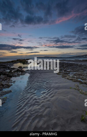 Compton Bay, Isle of Wight, Großbritannien. 30. September 2018. Einen schönen und stimmungsvollen Sonnenuntergang über dem Strand und Felsen an Compton Bucht auf der Insel Wight. Kühler herbst Wetter bringt einen bewölkten Himmel und Moody auf das Meer und die Klippen bei Ebbe. Sonnenuntergang Farben im nassen Sand reflektiert und Algen Felsen bedeckt. Quelle: Steve Hawkins Fotografie/Alamy leben Nachrichten Stockfoto