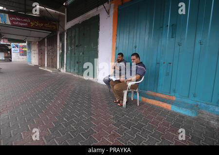 In Gaza. 1. Okt, 2018. Zwei palästinensische Männer sitzen vor einem geschlossenen Geschäft auf eine leere Straße im südlichen Gazastreifen Stadt Rafah, am Okt. 1, 2018. Die Palästinensischen Gebiete im Westjordanland, Gaza und den palästinensischen Städten in Israel Montag einen Generalstreik aus Protest gegen die kürzlich beschlossenen jüdischen Nationalstaat Gesetz in Israel erlebt. Credit: Khaled Omar/Xinhua/Alamy leben Nachrichten Stockfoto