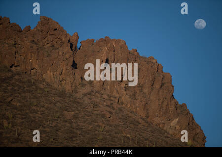 Vollmond, Sonnenaufgang Blick über die orange farbigen Felsen und spärliche Wüstenvegetation in San Carlos, Sonora, Mexiko. Luna Llena, Vista al Amanecer Stockfoto