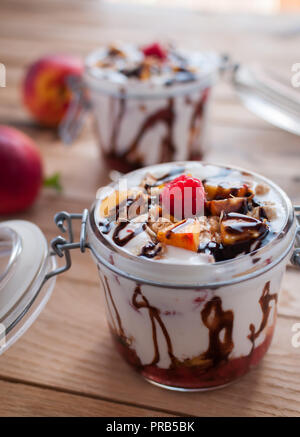 Close-up von Peach Parfait mit Joghurt, Müsli und Schokolade in einem Glas nachfüllen Stockfoto