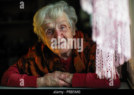 Porträt der alten Frau am Tisch sitzen. Stockfoto