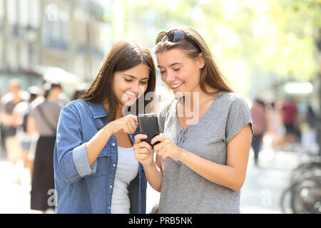 Zwei glückliche Freunde prüfen smart phone Inhalt auf der Straße Stockfoto