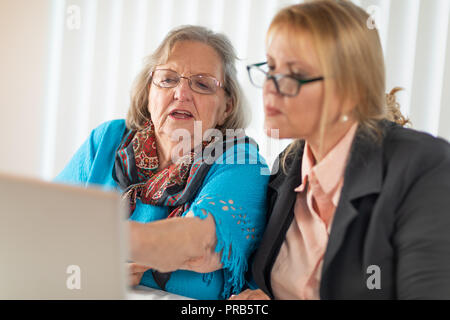 Frau helfen älteren Erwachsenen Dame am Laptop. Stockfoto