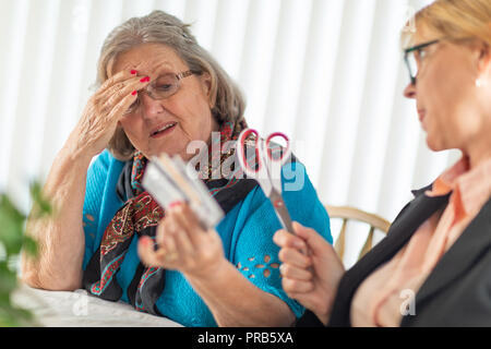 Finanzielle Berater Übergabe Schere zu den älteren Dame Holding Kreditkarten. Stockfoto