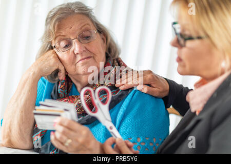 Finanzielle Berater Übergabe Schere zu den älteren Dame Holding Kreditkarten. Stockfoto