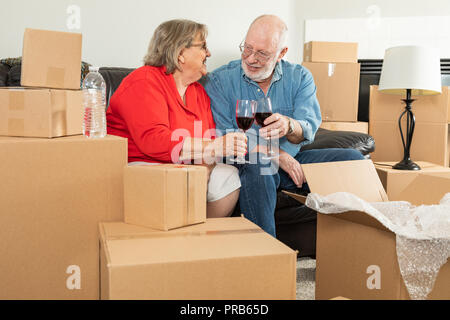 Senior nach Paar Toasten Weingläser durch bewegliche Kästchen umgeben. Stockfoto