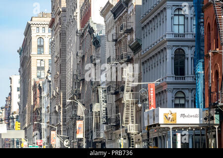 NEW YORK CITY, ca. 2018: Schilder und Banner für die Geschäfte am Broadway entlang hängen von der historischen Gebäude im Viertel SoHo in Manhattan Stockfoto