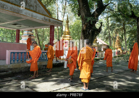 Mönche mit betteln Schalen unter Safranroben gehen Sie am Morgen in West Vietnam Stockfoto