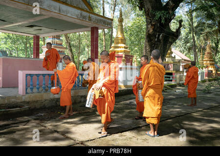 Mönche mit betteln Schalen unter Safranroben gehen Sie am Morgen in West Vietnam Stockfoto