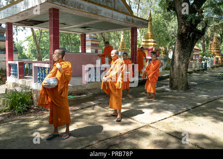 Mönche mit betteln Schalen unter Safranroben gehen Sie am Morgen in West Vietnam Stockfoto