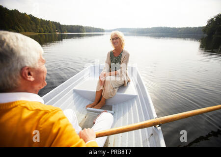 Lächelnde ältere Dame in Gläser, mit Liebe und Zärtlichkeit an Freund, Ruderboot und genießen Datum auf dem Boot Stockfoto