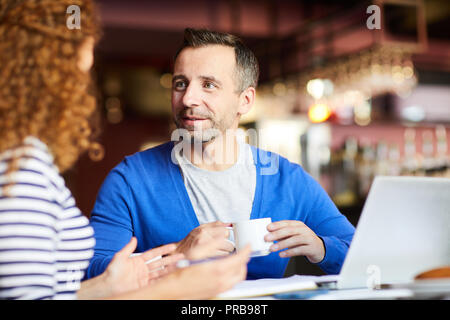 Inhalt gut aussehender Geschäftsmann mit Stoppeln Kaffee trinken und Frau während der informellen Treffen im Cafe Stockfoto