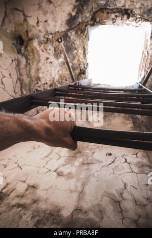 Grunge metal Leiter mit männlichen Hand, leere Turm Innenraum mit glühenden Ende Stockfoto