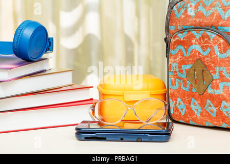 Schule Rucksack mit Schulmaterial. Bücher, Sandwich, Kopfhörer, Gläser und eBook auf Holztisch. Zurück zum Konzept der Schule. Stockfoto