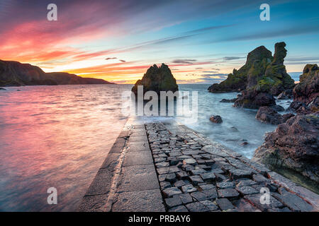 Ein feuriges Rot Sonnenuntergang über Pettico Wick Bay in St. Abbs in der Nähe von Eyemouth an der Ostküste von Schottland Stockfoto