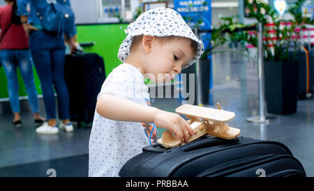 Portrait von wenig Kleinkind Junge spielt mit Miniatur Holz- flugzeug im Flughafen Terminal Stockfoto