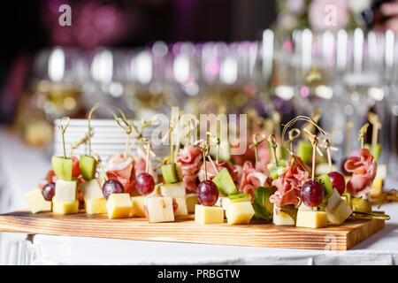 Das Buffet an der Rezeption. Gläser Wein und Champagner. Sortiment von Häppchen auf Holzbrett. Bankettservice. catering Essen, Snacks mit Käse, Schinken, Schinken und Obst Stockfoto