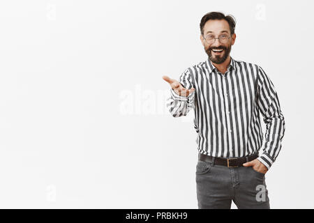 Freund, lange Zeit nicht sehen. Portrait von Ihnen überrascht stattlichen erwachsene Europäische in gestreiften Hemd und formalen Hose und zeigte mit Palm an Kamera und breit grinsend, Gruß vertraute Person auf der Konferenz Stockfoto