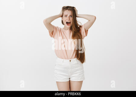 Mädchen Gefühl war schockiert, beraubt. Portrait von betäubt, junge Frau mit süssen Sommersprossen frustriert, Hände auf Haar und brüllen sich Kamera mit Erstaunen Ausdruck, verwirrt und ängstlich Stockfoto