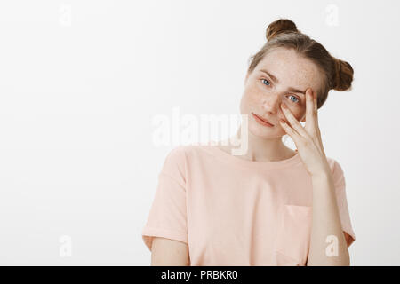 Mädchen versuchen, genau zuhören, was Freund zu sprechen. Portrait der Ruhe feminin Freundin mit freckels und blaue Augen, Hände halten Über die Hälfte der Fläche, spähen durch Finger und grinsend an Kamera Stockfoto