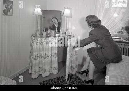 1950er Jahre die Frauen zu Hause. Eine Frau in ihrem Schlafzimmer zu Hause mit den Make-up-Tabelle. Ein Möbel entworfen, funktional für Make-up und Hairstyling. Schweden 1954. Ref 2797 Stockfoto