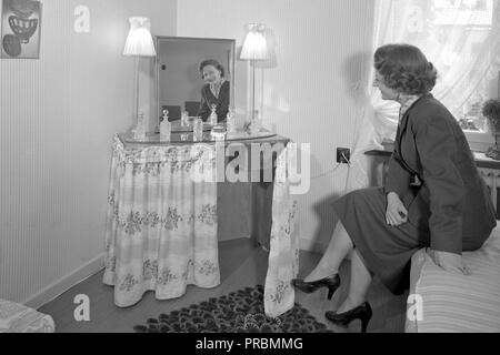 1950er Jahre die Frauen zu Hause. Eine Frau in ihrem Schlafzimmer zu Hause mit den Make-up-Tabelle. Ein Möbel entworfen, funktional für Make-up und Hairstyling. Schweden 1954. Ref 2797 Stockfoto