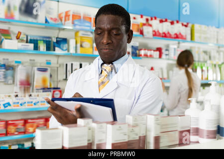 Professionelle positive männliche Apotheker in der Apotheke, Arzneimittel Inventar mit Kollegin Stockfoto