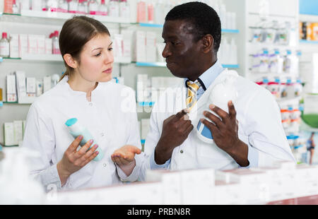Zwei zuversichtlich Apotheker diskutieren über Medikamente im Inneren der modernen Apotheke. Fokus auf den Menschen Stockfoto