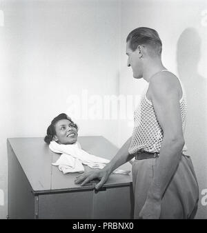 Beauty Care in den 1950er Jahren. Eine junge Frau sitzt in einer Dampfsauna, mit nur ihren Kopf, klemmt. Ein Mann mit der Behandlung steht neben ihr. Er trägt der besonderen Art ärmelloses Shirt mit der Stoff gestrickt wie ein Netz, vor allem unter ihrem Shirt verwendet werden. Schweden 1951. Foto Kristoffersson Ref. 102-1 Stockfoto