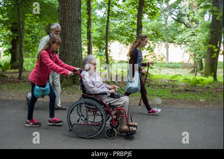 Alte Frau im Rollstuhl von ihrer Enkelin mit anderen Mitgliedern ihrer Familie an crathes Castle Aberdeenshire Scotland gedrückt wird Stockfoto