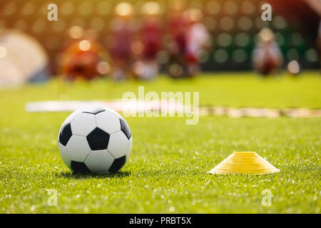 Fußball Fußball-Training Ausrüstung auf Training. Fußball Ausrüstung am Fußballplatz. Trainer und junge Fußballer im Hintergrund. Coaching Sie Stockfoto