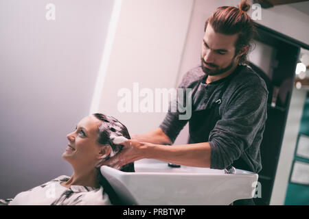 Junge Frau, neue Frisur an professionelle Haar styling Limousine. Friseur ist massieren Sie Ihren Kopf. Stockfoto