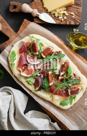 Flatbread Pizza mit Schinken, Feigen, Rucola auf Holzbrett. Ansicht von oben Stockfoto