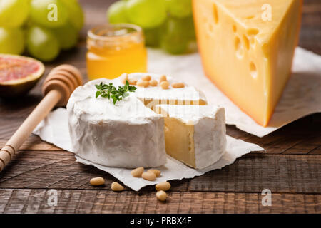 Käseplatte mit Brie, Camembert, maasdamer Käse und Obst grüne Trauben, Feigen, Pinienkernen und Thymian. Detailansicht. Gourmet Aperitif-platte Stockfoto