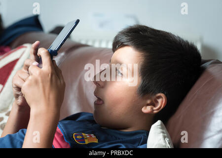 Okuläre Abweichung. Extreme Gaming o elektronische Gadgets verwenden könnten Kinder cross-eyed-boy spielt computer spiel auf tragbare Spielekonsole Stockfoto