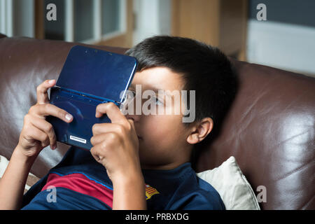 Okuläre Abweichung. Extreme Gaming und elektronische Gadgets verwenden könnten Kinder cross-eyed-boy spielt computer spiel auf tragbare Spielekonsole Stockfoto