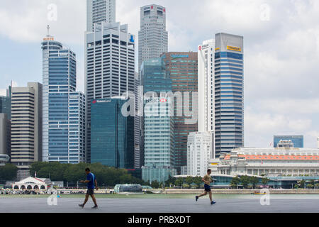 Männer laufen und laufen vor dem Hintergrund des Central Business District in der Nähe der Marina Bay Sands Uferpromenade. Singapur. Stockfoto