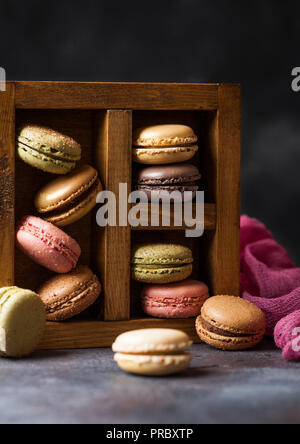 Dessert kuchen Macaron oder Makronen in vintage Holzkiste auf Stein Küche Hintergrund. Stockfoto