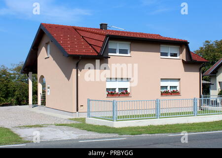 Voll kleine suburban Family House mit neuer Fassade renoviert, weißen Fenstern mit frischen Blumen, neues Dach und Dachrinnen, umgeben mit grauem Metall Stockfoto