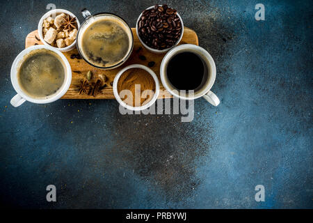 Drei Kaffeetassen, Bohnen, gemahlenen Kaffee und braunem Zucker. Dunkelblauem Hintergrund der Ansicht von oben Platz für Ihren Text Stockfoto