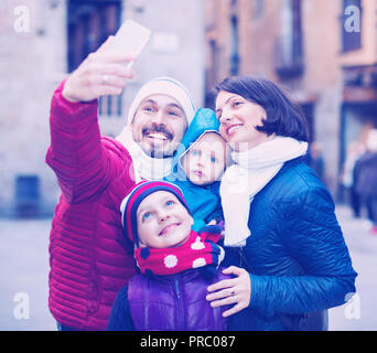 Gerne fröhliche positive Familie mit zwei Kindern zu Fuß die Stadt und tun selfie im Herbst Stockfoto