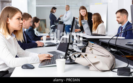 Junge angenehm positive Geschäftsfrau konzentrierte sich auf die Arbeit mit Laptop im Coworking Space Stockfoto