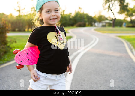 Mode Mädchen Kind mit Skateboard das Tragen einer Sonnenbrille und hipster Shirt. Stockfoto