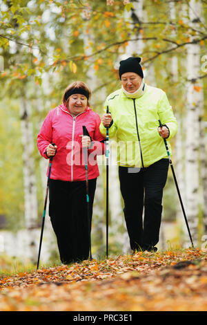 Reife Frau zu Fuß in einem Herbst Park während einer skandinavischen Spaziergang Stockfoto