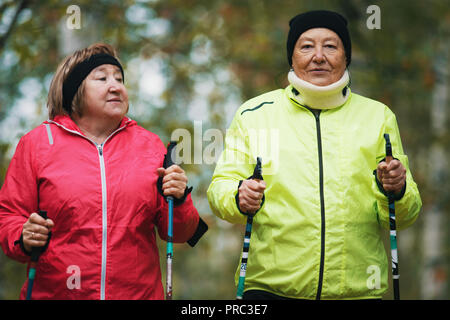 Reife Frauen sind im skandinavischen Wandern im Herbst im Park eingerückt Stockfoto